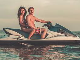 A woman and a man laughing and posing on a jet ski