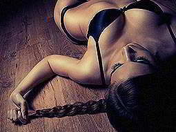 A woman lying on the ground in her underwear, pulling on her hair