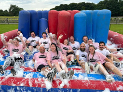 A group of people covered in bubbles and soap on an inflatable at It's a Knockout