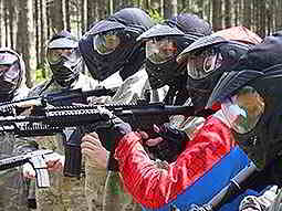 A line of people wearing overalls and full-face masks aiming AR15-style airsoft rifles