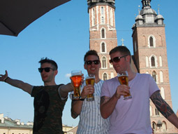 Three men having a drink on a pub crawl in Krakow