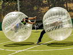 Two people bouncing off each other in inflated zorbs 