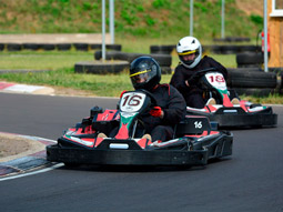 Two people driving go karts around a track in Bournemouth