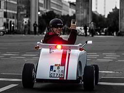 The back of a man driving a hot rod in the streets