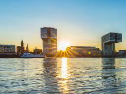 A view of modern waterside buildings with a low sun behind