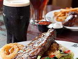 A steak meal next to a pint of Guinness, with more food and drink in the background