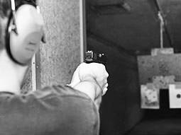 blakc and white image of man with hand gun at an indoor shooting range