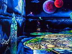 A glow-in-the-dark indoor mini golf course, with murals on the walls and floor