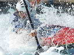 A person paddling a kayak through foamy rapids