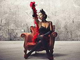 A woman sitting in a leather chair, posing with a red feather boa