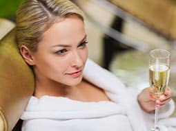 A woman wearing a white robe and holding a glass of champagne 