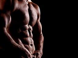 A naked male torso to a black backdrop