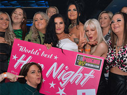 People dancing on a dancefloor holding a Hen Night sign