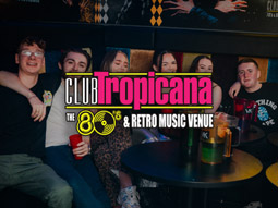 A group of people sitting at a table in a club, with drinks