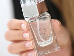 A woman's hand, holding a perfume bottle
