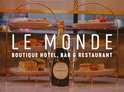 Two sets of afternoon tea with cake, sandwiches and scones and a champagne bottle in the middle at Le Monde in Edinburgh