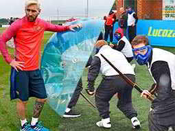 Split image of Messi stood next to a blue inflatable zorb, and a group of men playing archery tag