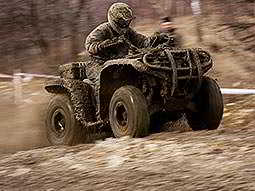 A man in camouflage quad biking on a dirt path