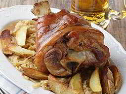 A traditional German meal on a plate with a beer in the background