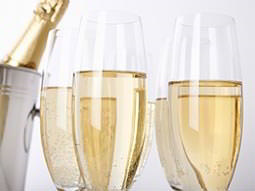 Full champagne flutes next to a silver bucket with champagne in