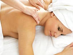 A woman receiving a back massage, with a towel on her head