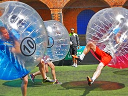 People playing in pink and blue zorbs on a pitch