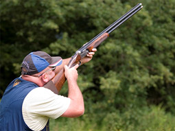 Someone aiming a gun at a clay pigeon