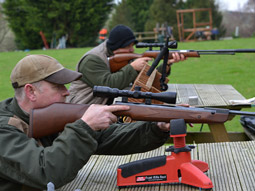 Two people aiming their air rifles at a target outside