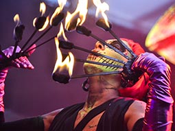 A person blowing on fire whilst juggling