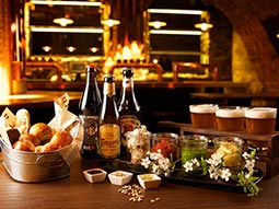 A banquet set up on a wooden table of beers and bread