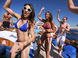 Men and women dancing on the deck of a boat in swimwear