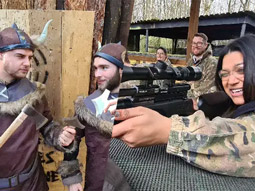 A split image of two men facing each other with axes and a woman aiming a gun at a target