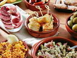 Some tapas food including ham and olives on a table 