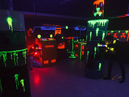 Two people holding laser guns in a dark room with multicoloured lights