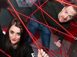 A man and a woman in between red cord in a game at GoQuest Challenge Zone in Dublin