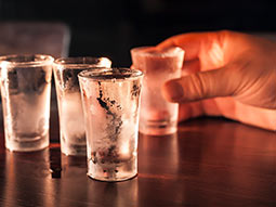 A close up of someones hand holding a shot glass