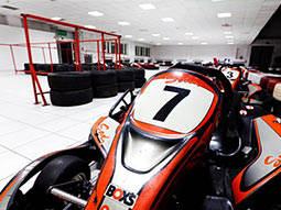 A close up of a go kart with tyres in the background