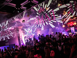 A large group of people in a nightclub with various coloured lights