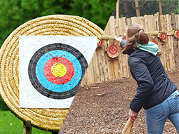 A split image of an archery target and someone throwing an axe at a target