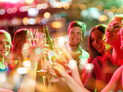 A man and four women holding glasses of alcohol up, cheering