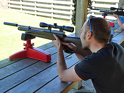 Man in black T-shirt, aiming a rifle 