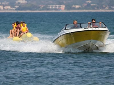 Image of a speed boat pulling people on a banana boat in the sea