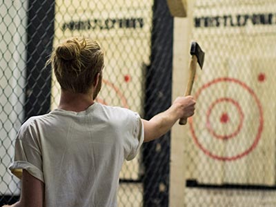 Image of a man throwing an axe at the target on the wall