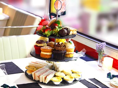A serving tray with three tiers of cakes and sandwiches
