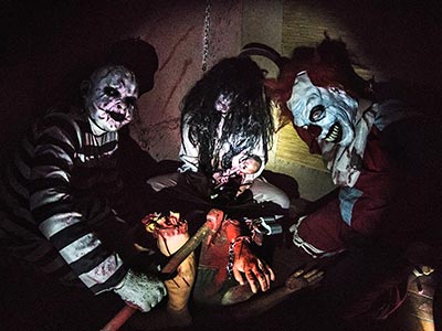 A dark room with three people dressed up in scary costumes