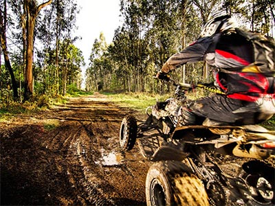Someone on a quad bike riding through muddy terrain