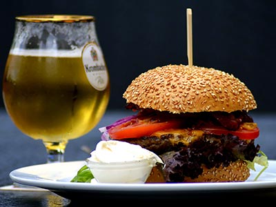 A burger on a plate, next to a glass of beer