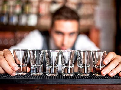 A bartender lining up some shot glasses on the bar