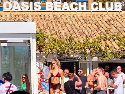 People sat having drinks with the Oasis Beach Club logo overlayed