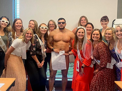 A group of hens with artwork in their hands, stood posing next to a nude life model